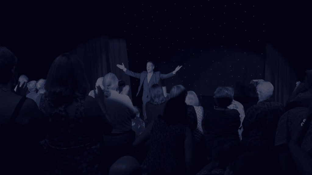Mentalist Joe Skilton gets a standing ovation. Dark blue filter added.