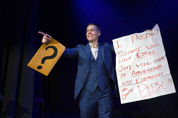 Mentalist Joe Skilton points to the audience while holding a prediction.