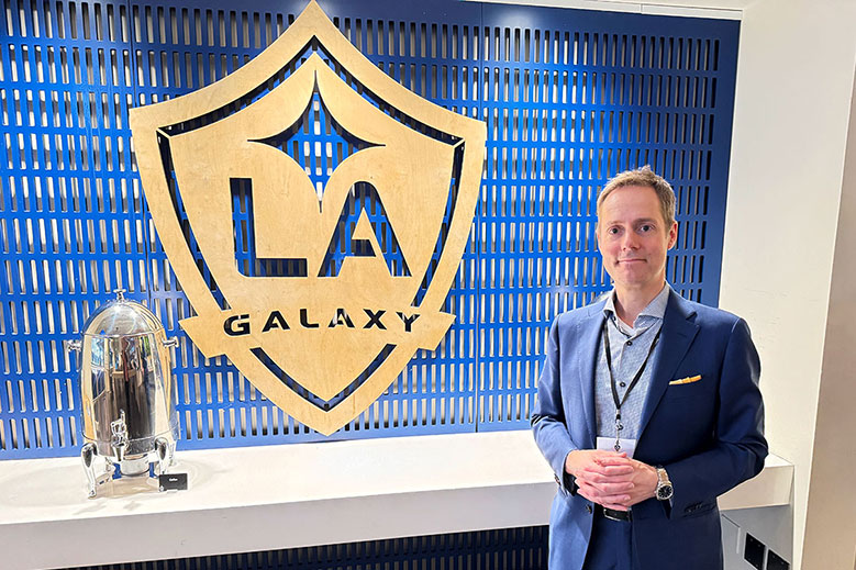 Los Angeles based mentalist Joe Skilton standing in front of the LA Galaxy logo in the Kia Champions Lounge.