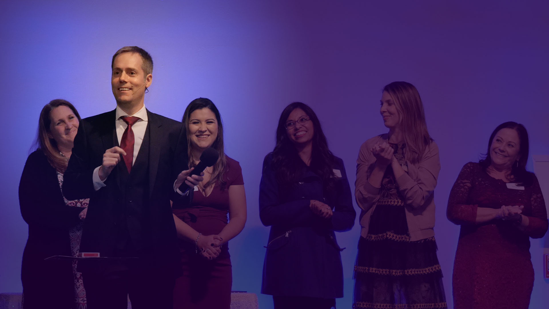 Image of corporate mentalist Joe Skilton standing on stage with 5 audience volunteers.