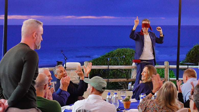 Joe Skilton reads the minds of CEOs while wearing a blindfold with the ocean as a backdrop.
